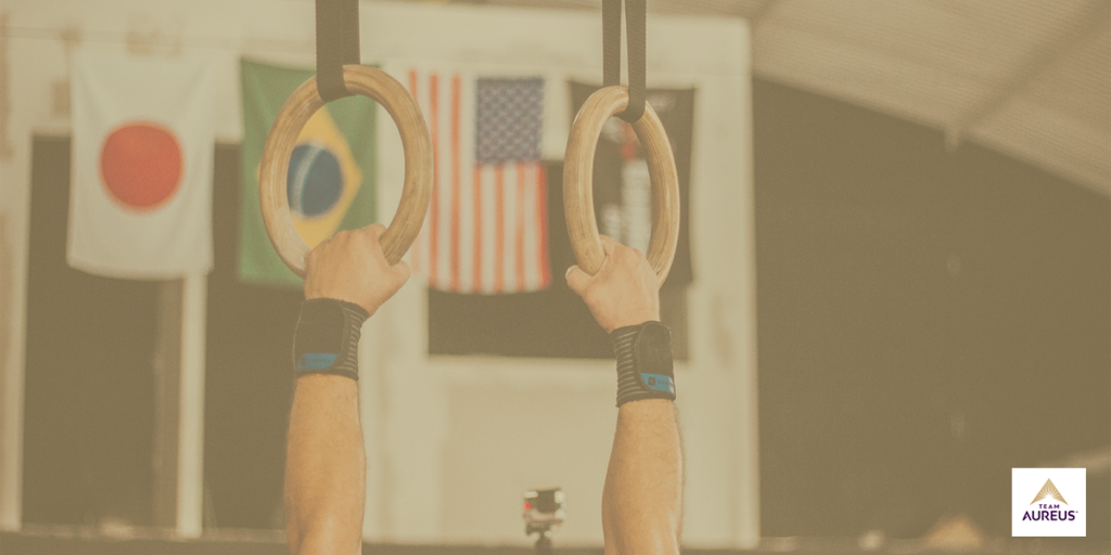 Hands holding gymnastic rings with American flag in background